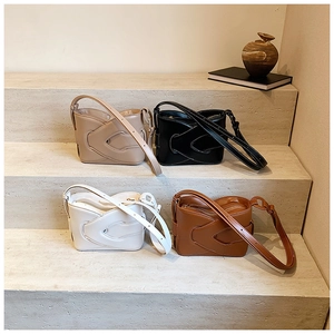 Minimalist bucket bags in four colors featuring interlocking leather design on stone steps