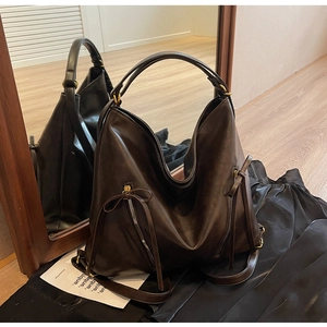 Detail of dark brown vintage faux leather tote with long tassel accents and decorative zippers
