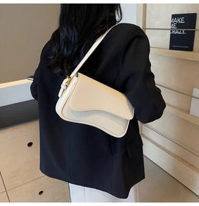 Close-up of cream white lychee pattern leather underarm bag with wavy flap and metal buckle