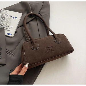 Close-up of brown suede shoulder bag with embossed brand text and dual handles