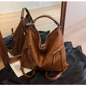 Close-up of brown leather backpack featuring vertical zippers and long leather drawstring