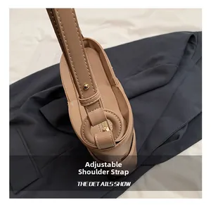 Close-up of adjustable wide strap with golden metal buckle and white stitching on beige bag