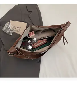Vue macro de l'intérieur spacieux de ce sac cabas en daim marron foncé avec objets