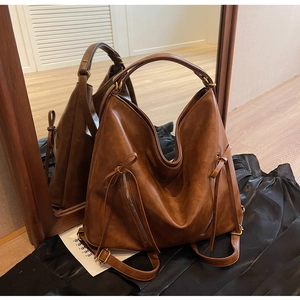 Detail view of vintage dark brown tote backpack with metal zippers and elegant tassels