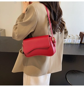 Detail view of red lychee leather underarm bag with unique wavy asymmetrical flap design