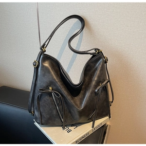Close-up of black retro leather bag featuring dual zip pockets and bow details