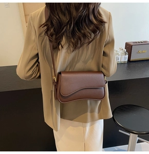 Detail view of coffee leather crossbody bag with asymmetric flap and adjustable strap