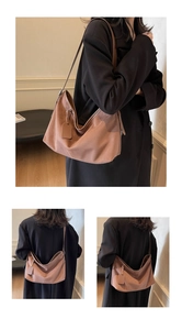 Macro detail of brown suede hobo bag with wide strap and decorative hanging tag