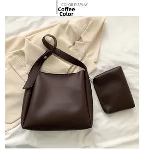 Detail view of brown minimalist large tote bag set with small pouch on white fabric
