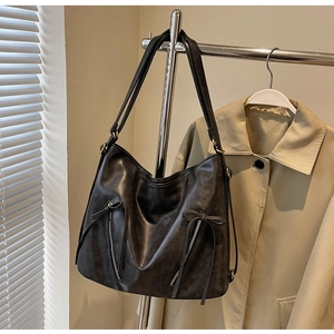 Detail of vintage black leather tote bag featuring side zippers and bow knot accents