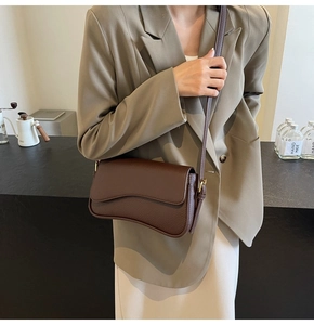 Close-up of brown litchi grain leather shoulder bag with gold metal buckle