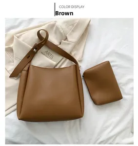 Detail view of caramel brown tote bag and small pouch on minimalist white background