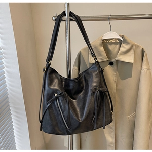 Detailed view of black leather tote bag featuring retro zippers and bow decoration
