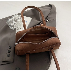 Close-up of brown suede shoulder bag with metal zipper and organized interior pocket