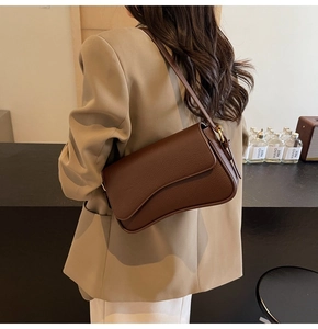 Detail of a brown lychee-patterned leather shoulder bag with gold metal buckle