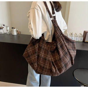 Détail d'un grand sac cabas à carreaux marron avec boucle en argent dans un café