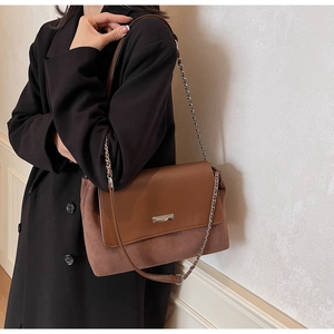 Detail view of retro brown shoulder bag showing leather texture and metal chain strap