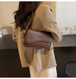 Brown litchi leather shoulder bag with curved bottom and gold hardware on female model