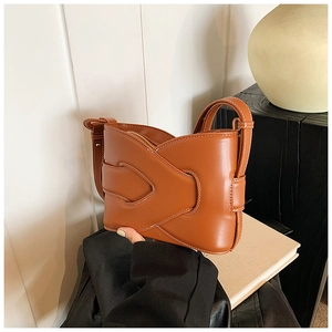 Detail of a brown leather crossbody bucket bag with white contrast stitching and a zipper