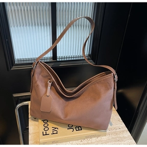 Minimalist brown matte faux leather tote bag with adjustable strap for women in a luxury setting