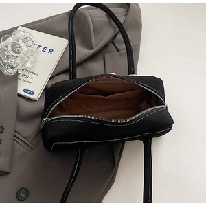 Detail view of black shoulder bag with contrast stitching and spacious brown fabric lining