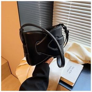 Detail of black PU shoulder bag with unique geometric folds and white contrast stitching