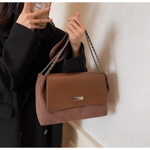 Detail of brown leather and suede patchwork shoulder bag with elegant silver logo plate