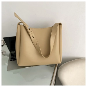 Detail of adjustable wide shoulder strap and silver metal buckle on beige tote bag