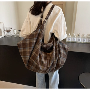 Détail d'un grand sac fourre-tout souple à carreaux bleu et marron sur un mannequin