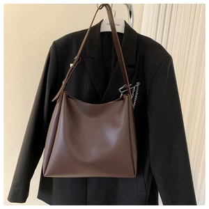 Detail of minimalist dark brown tote bag hanging with stylish black blazer