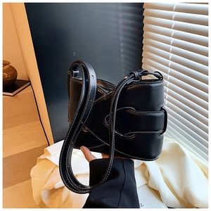 Close-up of black leather bucket bag with white contrast stitching and unique buckle detail