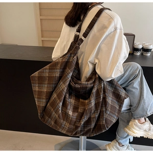 Détail d'un grand sac hobo vintage à carreaux avec bandoulière réglable dans un café cosy