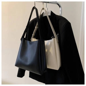 Detail view of black and off-white faux leather tote bags with adjustable straps on hangers