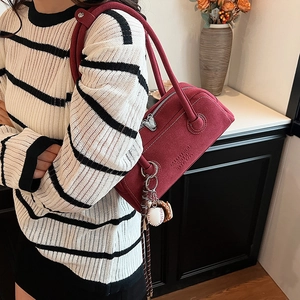 Minimalist burgundy suede underarm bag with baseball charm and stylish white stitching