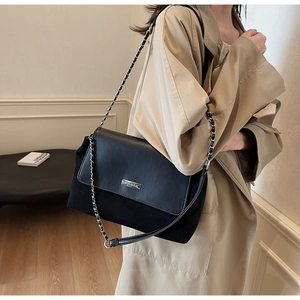 Detail of vintage shoulder bag with silver YOUBER plaque and metal chain strap