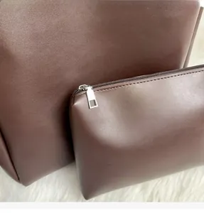 Detail view of the deep brown leather tote with a small matching zipper pouch and silver hardware