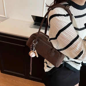 Brown matte underarm bag with contrast stitching and baseball bat charm detail