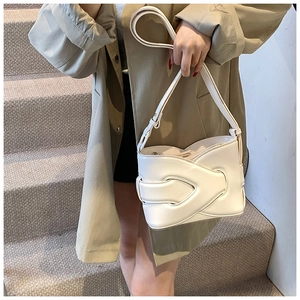Chic beige woven bucket bag worn by model with khaki trench coat in urban stairs setting