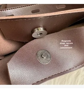 Detail of magnetic snap closure on dark brown leather bucket bag with metallic hardware