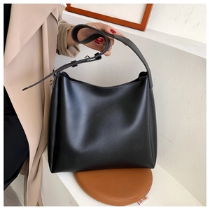 Close-up of black leather hobo bag with silver metal buckle held by model