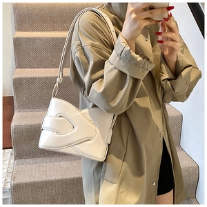 Detail of white leather shoulder bag with artistic layered design and wide strap