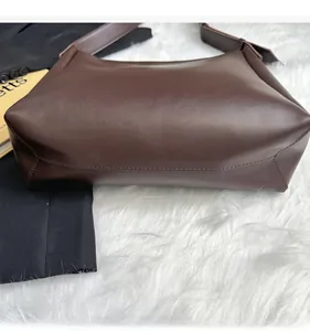 Detail shot of the reinforced bottom and smooth leather texture on dark brown bucket bag