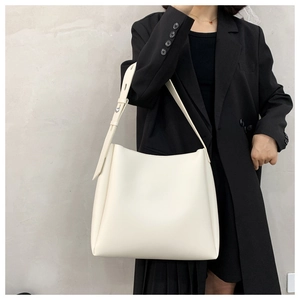 Detail of minimalist cream hobo tote bag with silver buckle on a wide shoulder strap