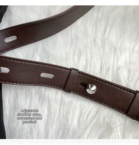 Detail of adjustable dark brown leather shoulder strap with silver metal buckle on white fur