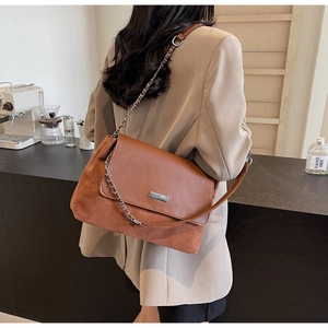Close-up of vintage brown shoulder bag with metal chain strap and brand nameplate
