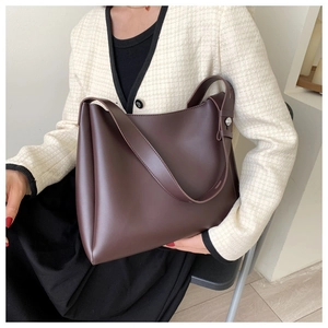 Detail of dark brown leather tote bag with wide strap and silver metal studs decoration
