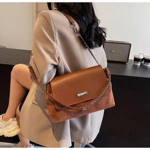 Brown vintage underarm bag with mixed leather texture shown on a female model shoulder