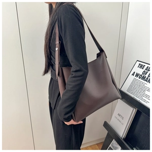 Large dark brown leather tote bag with wide strap styled on shoulder for work commute