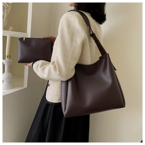 Detail of dark brown faux leather tote bag and matching pouch on a minimalist background