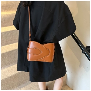 Detail of brown leather crossbody bag with interlocking strap and sleek metal hardware
